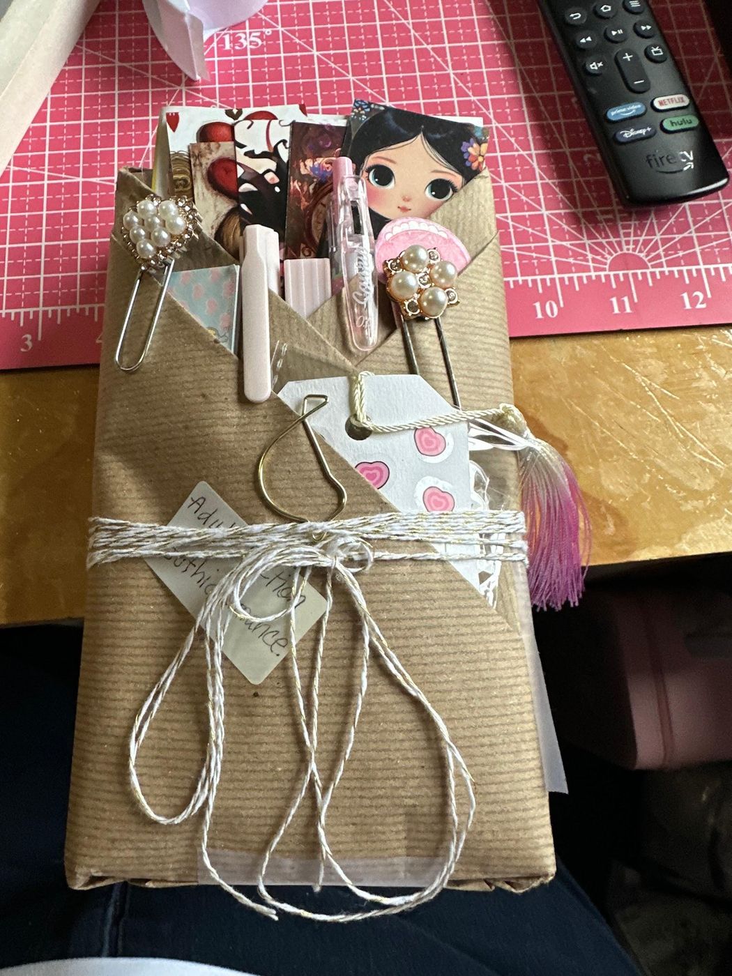 A book wrapped in brown paper and twine with bookmarks and pens